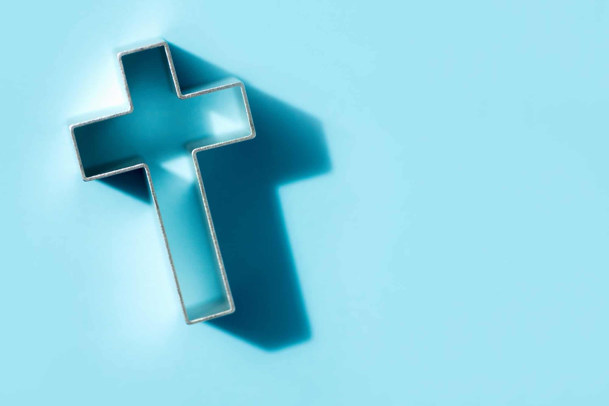 Church worship, salvation concept. Silhouette of christian cross on blue background, soft bokeh