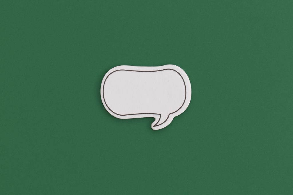 Paper speech bubble on a green background. Top view with copy space. Flat lay.